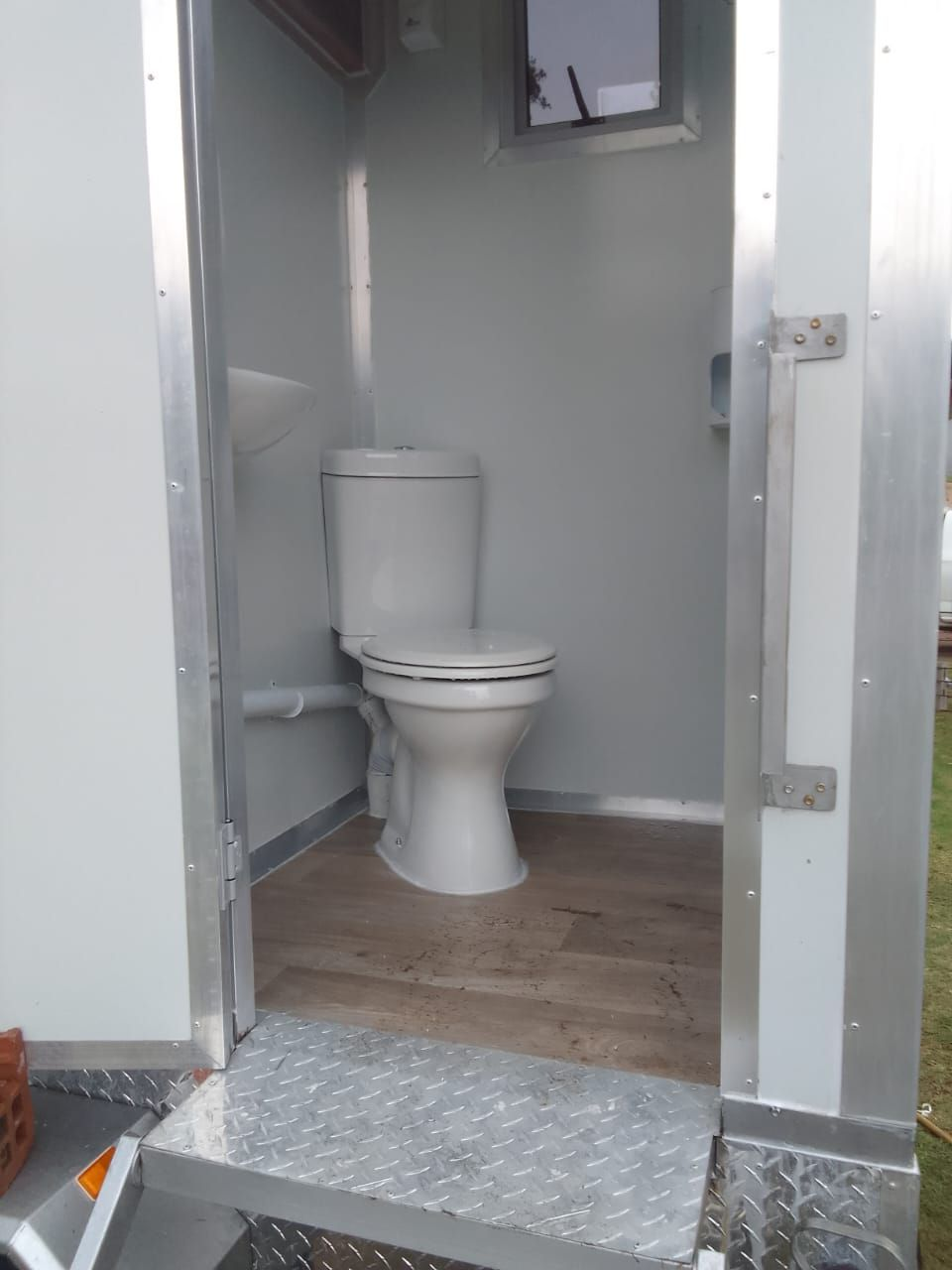 Inside a finished mobile toilet trailer with toilet and basin